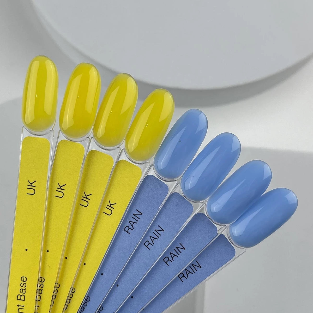 Yellow and blue gel nail polish swatches on labeled display sticks for manicure