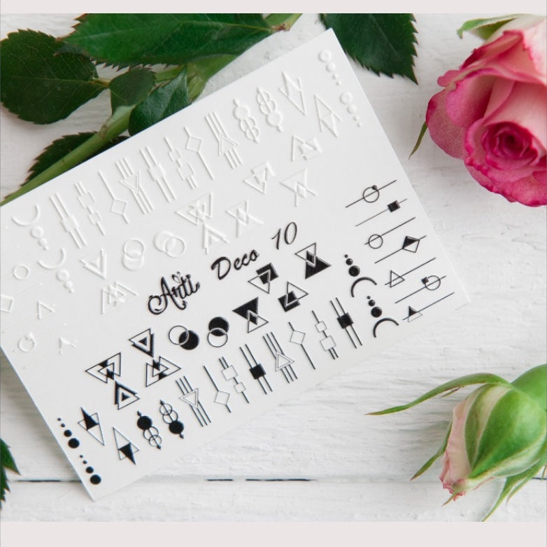 Geometric art deco nail stickers sheet with black and white designs on white background, next to pink roses.