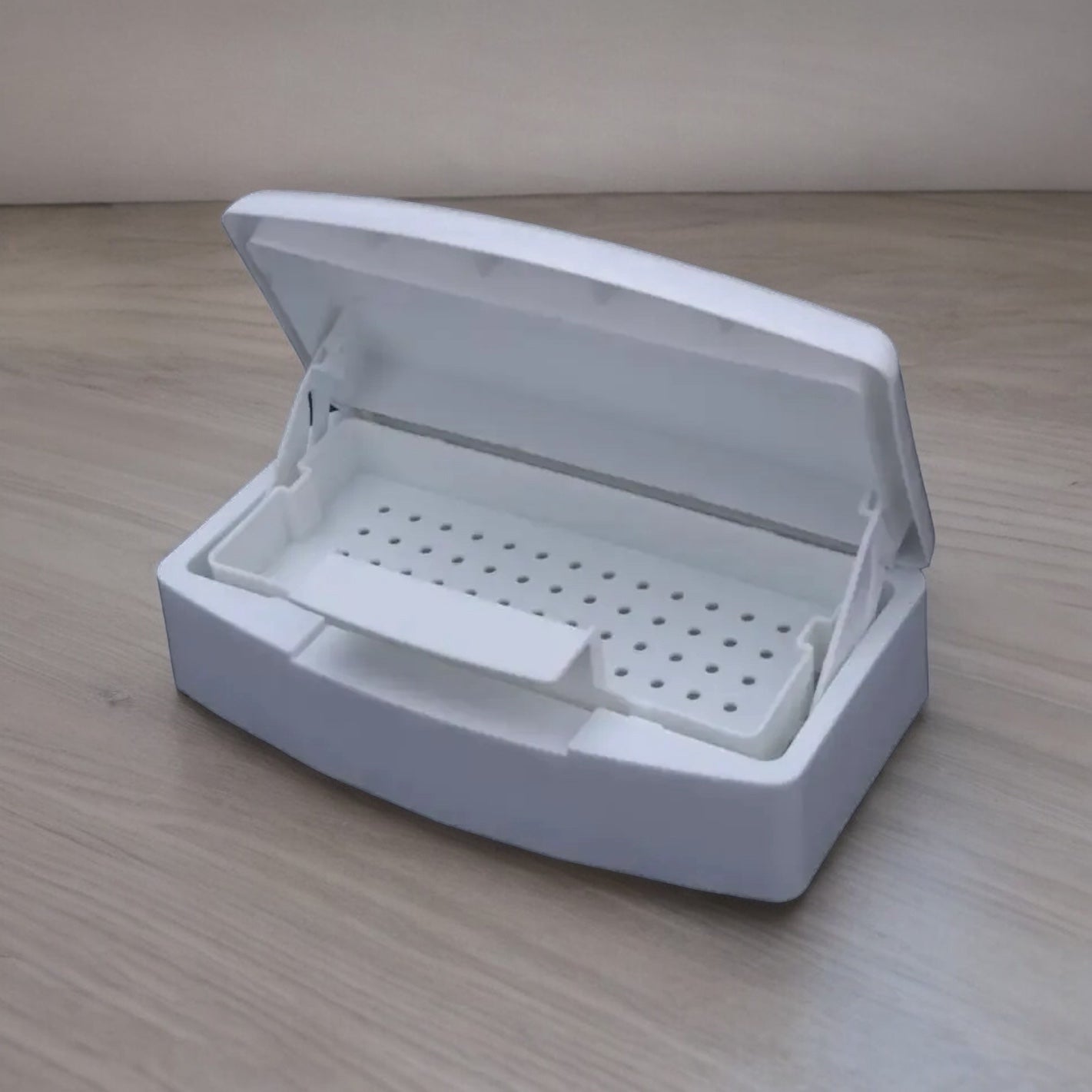 White plastic manicure tool sterilizer box with open lid on wooden surface