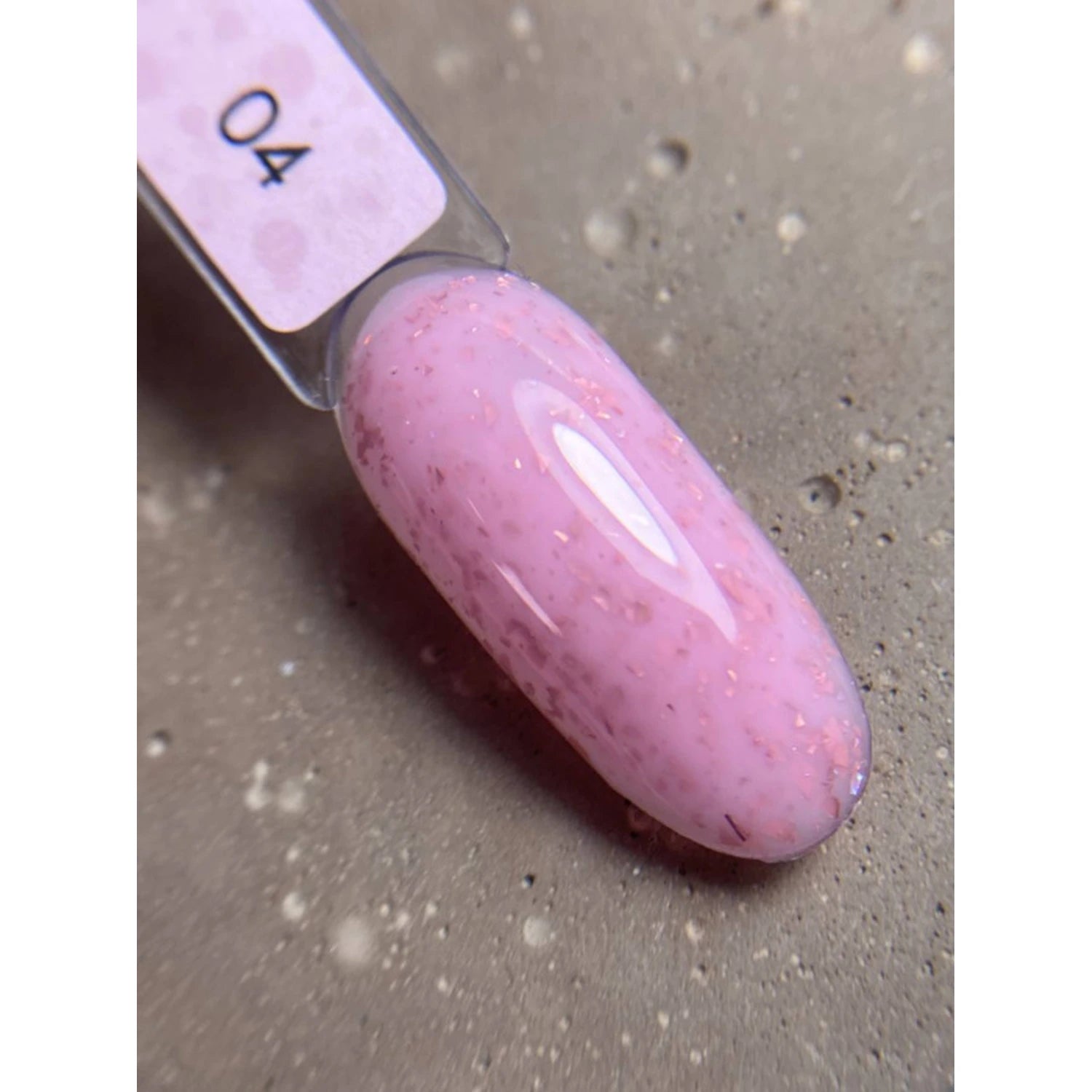 Swatch of glossy pink UV gel polish with subtle glitter flakes on a nail display stick