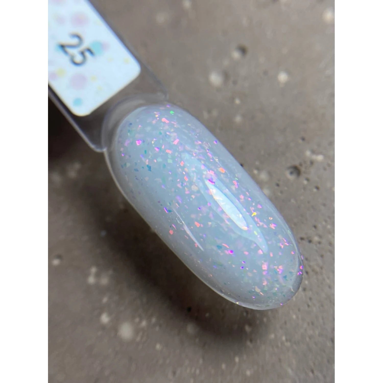 Swatch of sheer white UV gel polish with iridescent glitter flakes on nail tip.