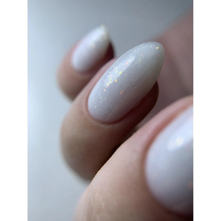 Close-up of fingernails with white UV gel polish and subtle iridescent glitter.