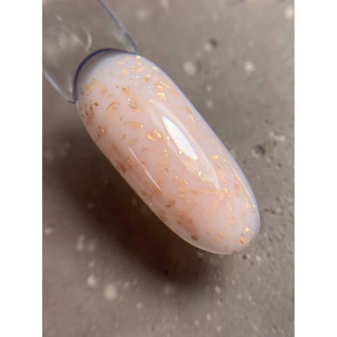 Swatch of milky pink UV gel nail polish with subtle gold flakes on sample tip