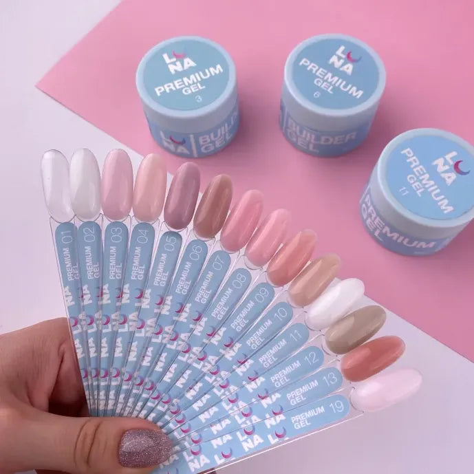 Hand holding nail color swatches with nude gel polish shades near premium builder gel jars