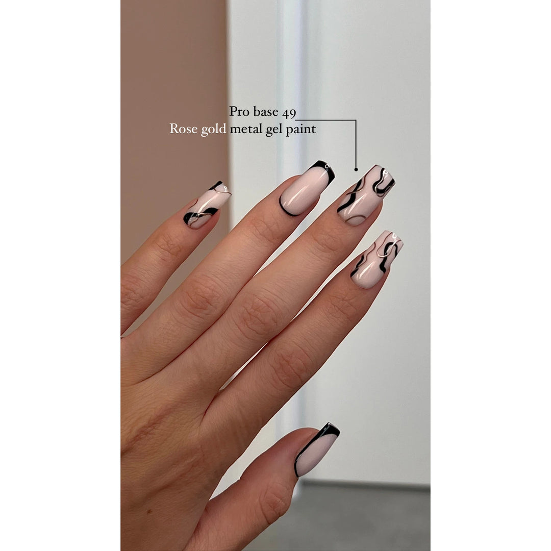 Hand with square gel nails, nude base, black abstract lines and tips, rose gold accents