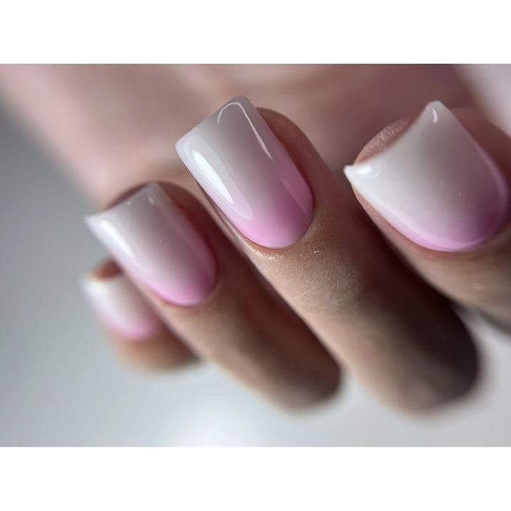 Close-up of manicured nails with pink and white ombre gel polish, glossy finish