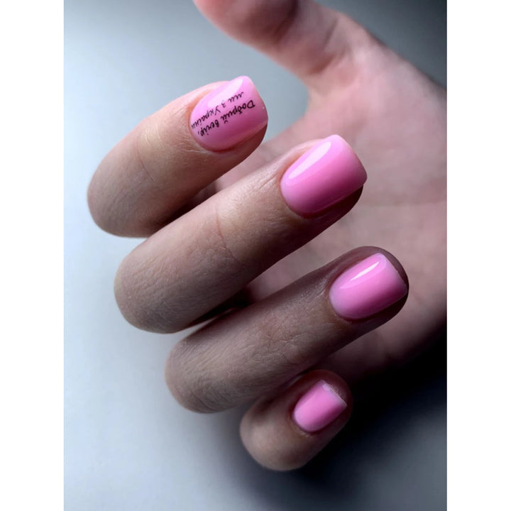 Hand with manicured nails painted glossy light pink UV gel polish