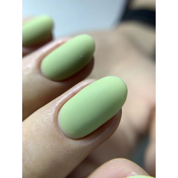 Close-up of nails with matte pastel green gel polish, professional manicure