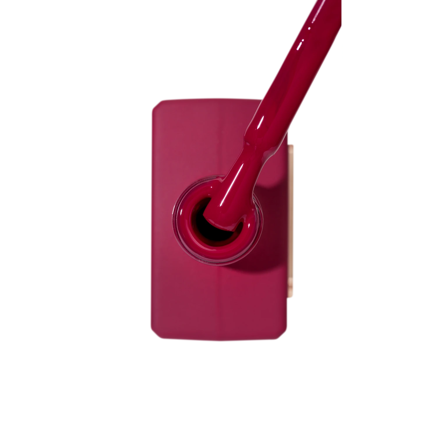 Open bottle of deep pink gel nail polish with brush, viewed from above