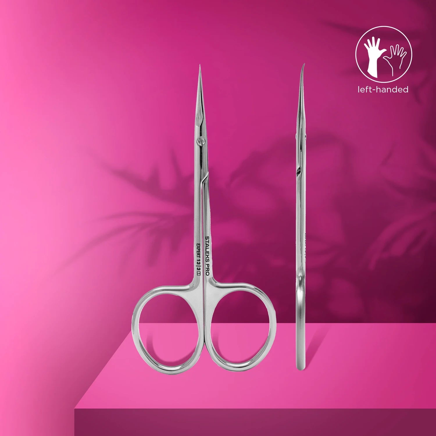 Left-handed stainless steel cuticle scissors for manicure on a pink background.