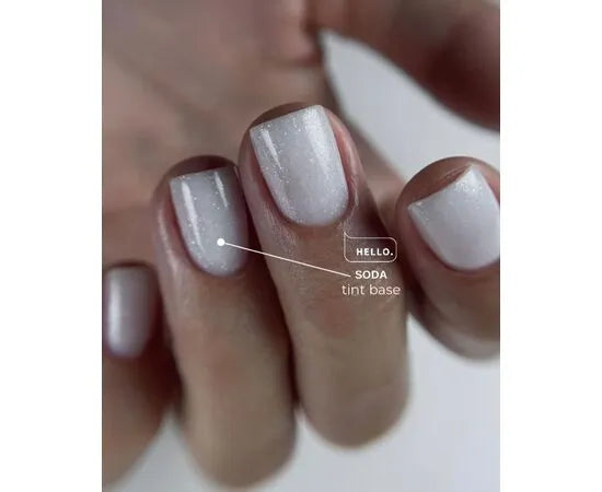 Close-up of fingernails with shimmery white gel polish, labeled soda tint base manicure.