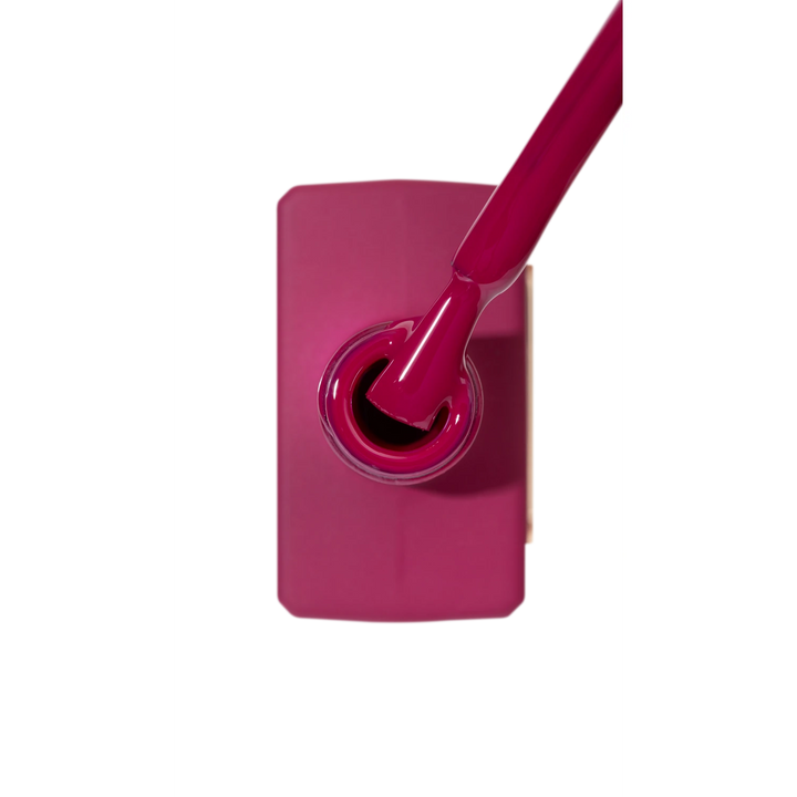 Deep pink gel nail polish bottle with brush, manicure product close-up