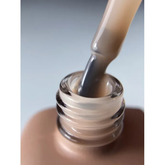 Close-up of nude gel nail polish bottle with brush applicator, manicure product