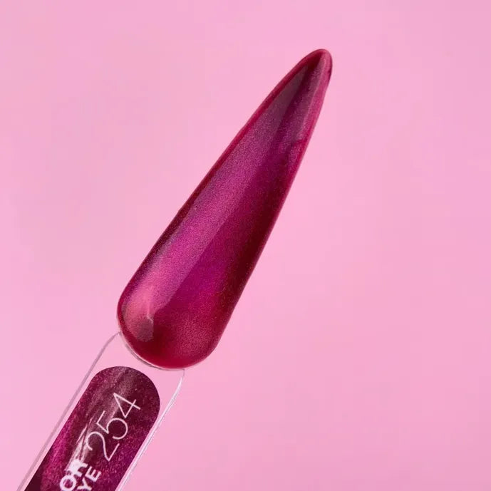 Cat eye gel polish swatch in metallic magenta on nail display stick, pink background
