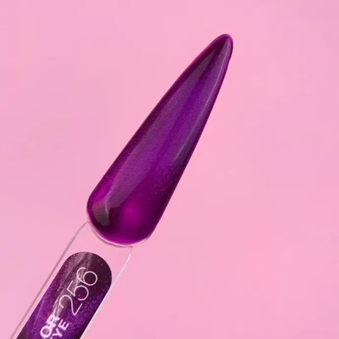 Purple cat eye gel nail polish swatch on display stick against pink background