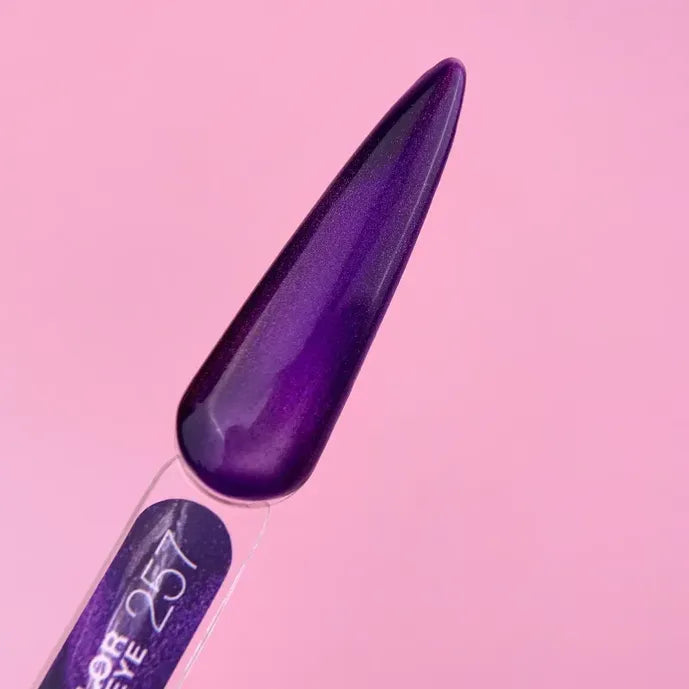 Purple cat eye gel nail polish swatch on clear tip against pink background