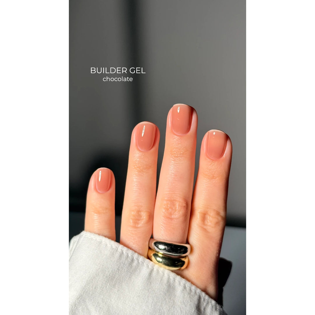 Hand with short nails painted in chocolate builder gel polish, manicure close-up