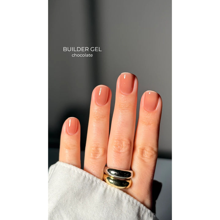 Hand with short nails painted in chocolate builder gel polish, manicure close-up