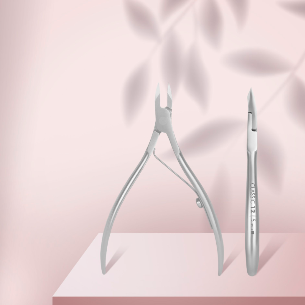 Stainless steel cuticle nippers for manicure and pedicure on a pink background.