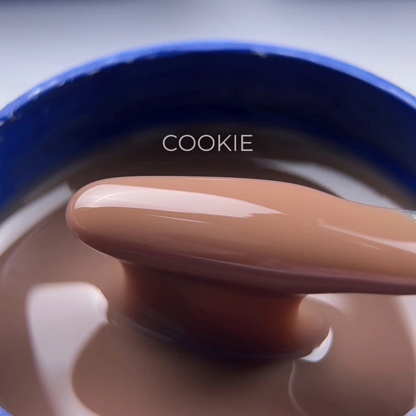 Close-up of nude brown gel nail polish on spatula, labeled Cookie, in a blue jar