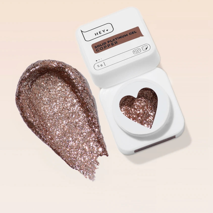 Copper glitter solid gel for nails in a heart-shaped container with a swatch on a beige background