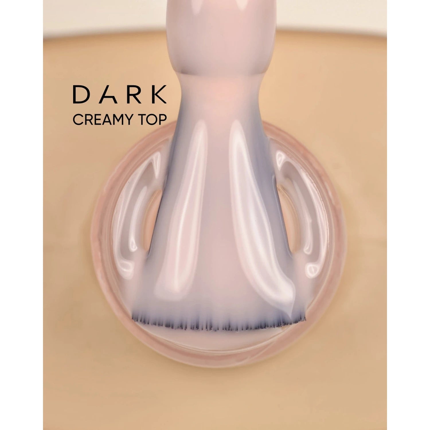 Close-up of brush with creamy gel nail polish labeled dark creamy top