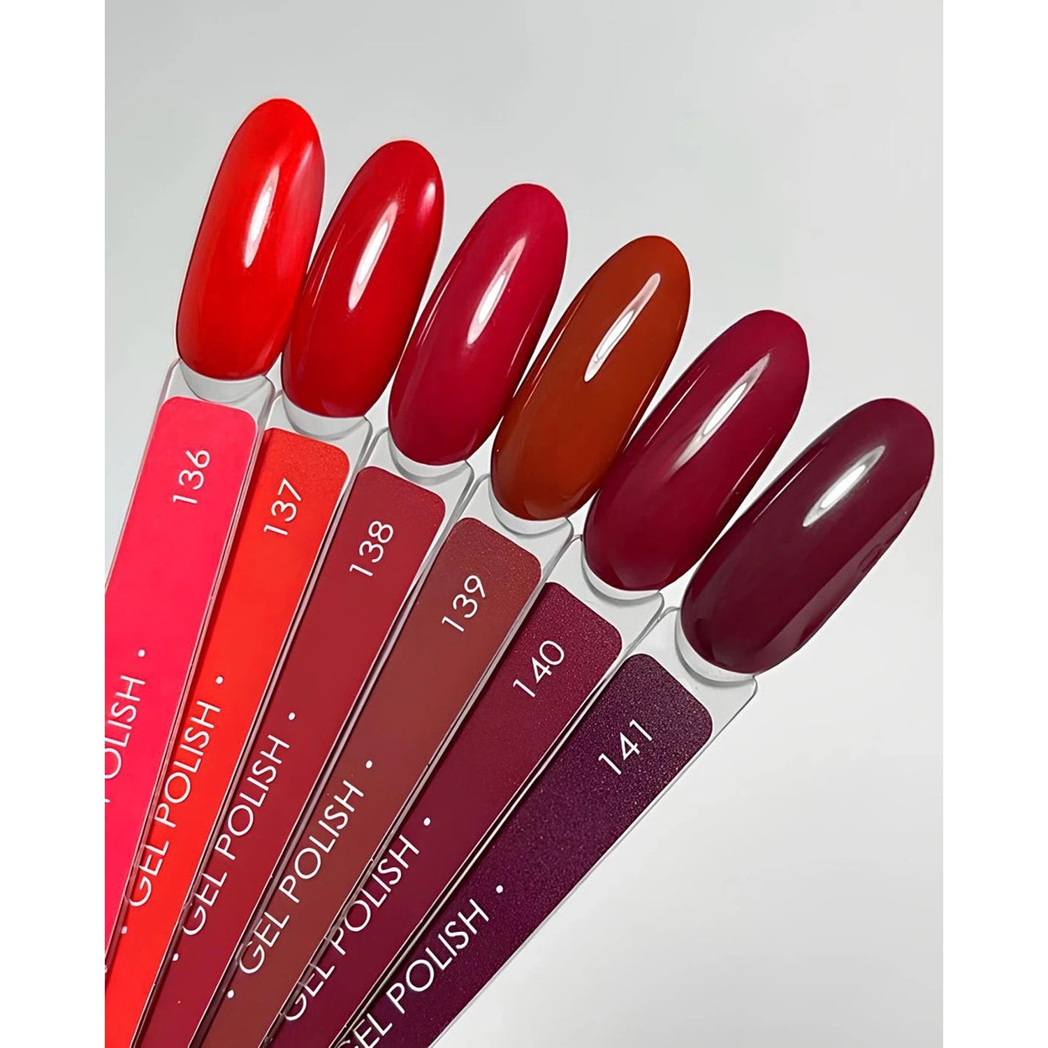Assorted red gel polish color swatches for nails, numbered 136 to 141, on white background.