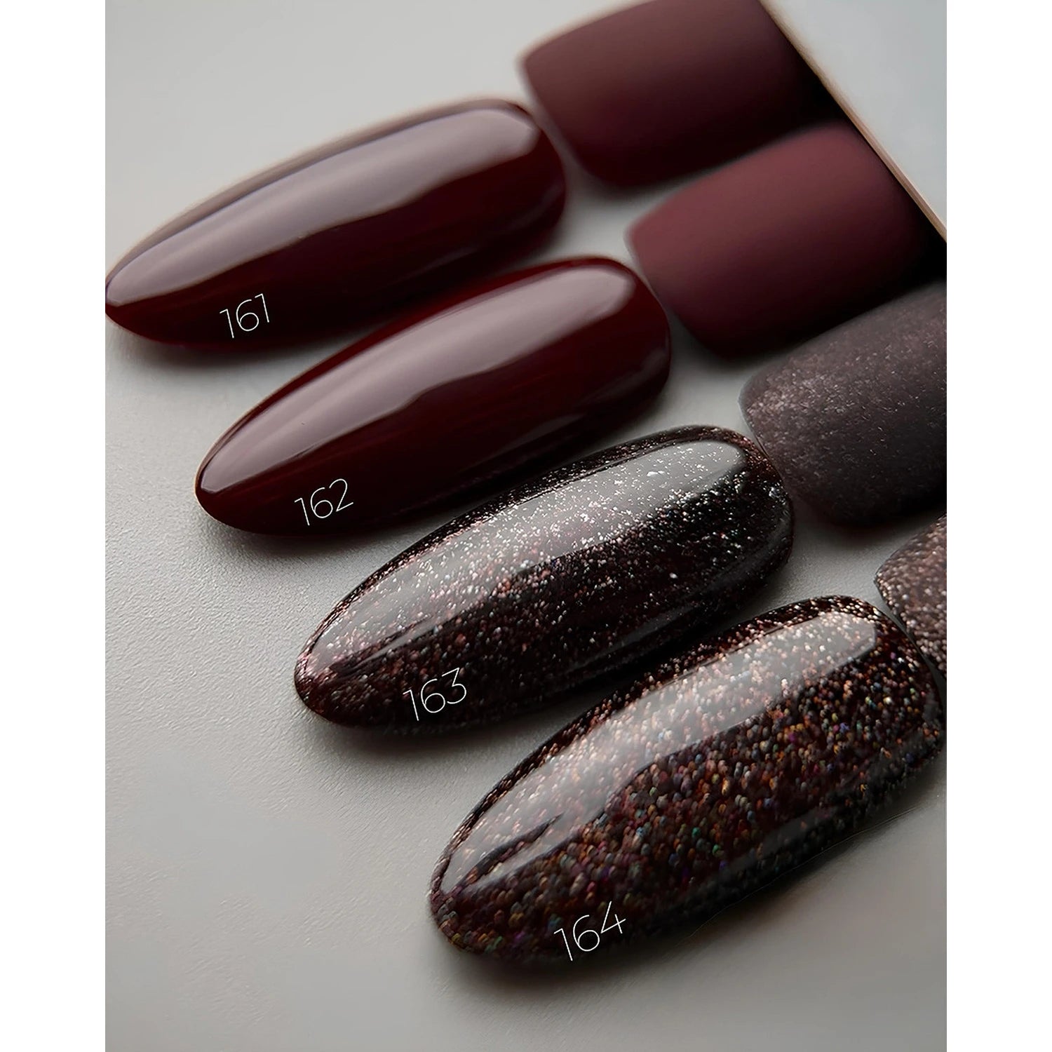 Four artificial nail tips in wine red and glittery dark gel polish shades, labeled 161-164.