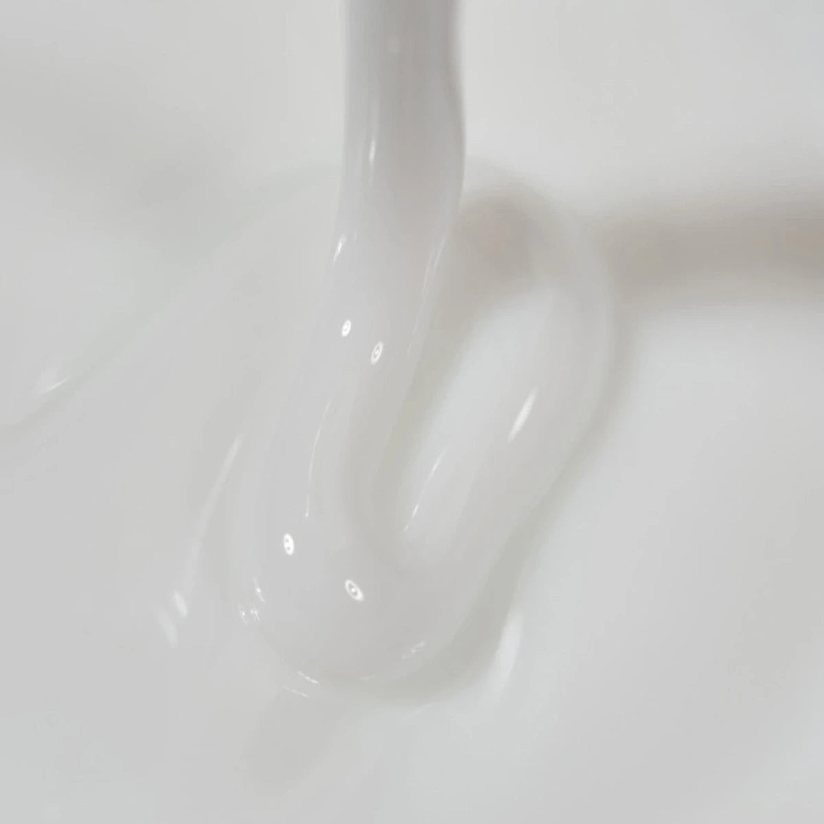 Close-up of thick white nail gel flowing, perfect for UV gel manicure application.