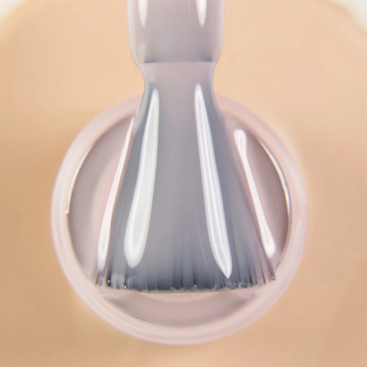 Close-up of nail polish brush applying nude gel polish for manicure