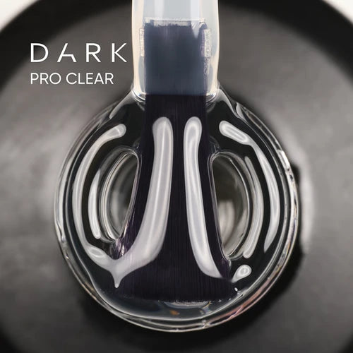 Close-up of brush applying dark pro clear UV gel nail polish in a round bottle