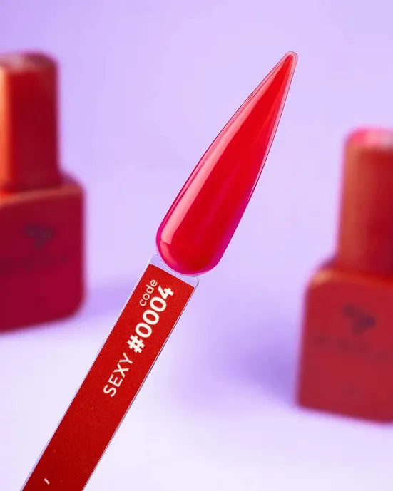 Red gel nail polish swatch on stick, labeled code #0004, with bottles in background
