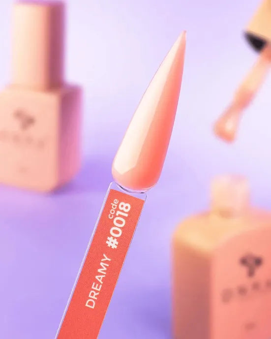 Swatch of dreamy peach nude gel nail polish, code 0018, with bottles in blurred background.