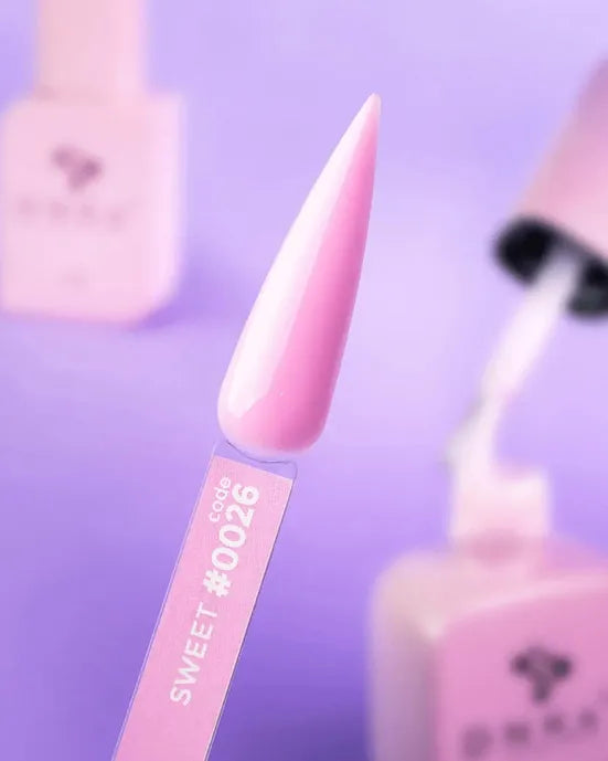 Pink nail gel polish sample labeled code 0026, surrounded by matching manicure bottles
