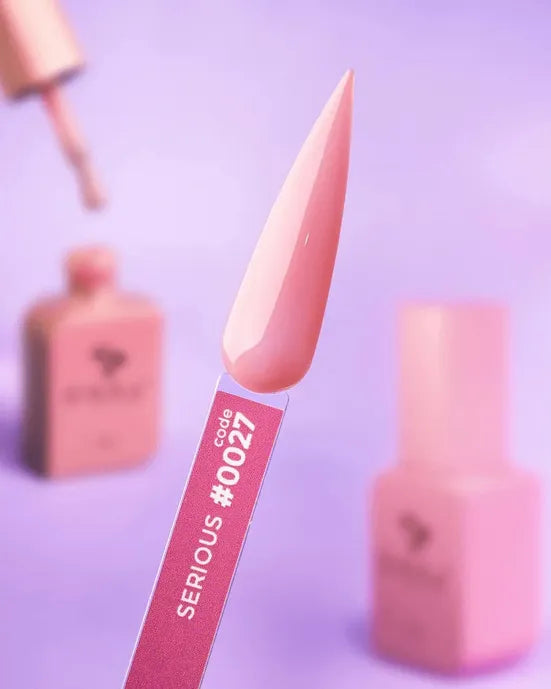 Pink gel nail polish swatch on stick labeled Code 0027, with matching bottles in background