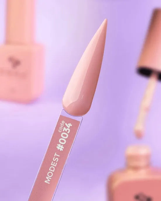 Nude pink gel nail polish swatch sample labeled Modest code #0034 with polish bottles