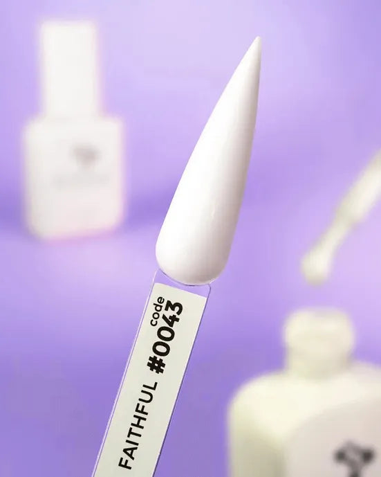 White gel nail polish sample on display stick labeled code 0043, manicure tools in background
