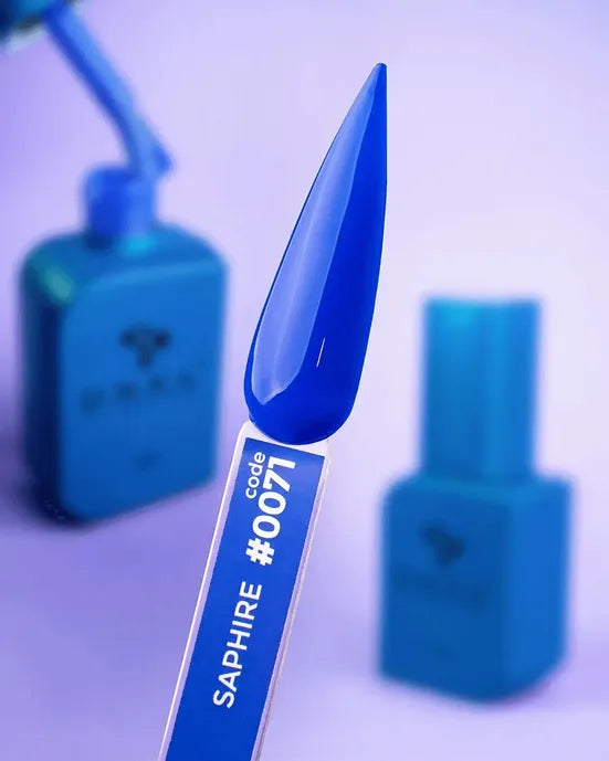 Sapphire blue gel nail polish swatch stick with code 0071, manicure supplies in background