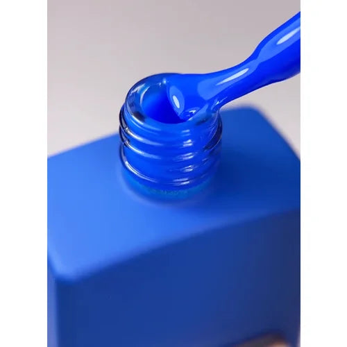 Open bottle of vibrant blue gel nail polish with applicator brush