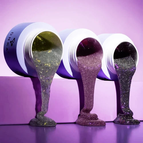 Three glittery containers with lids on a purple background