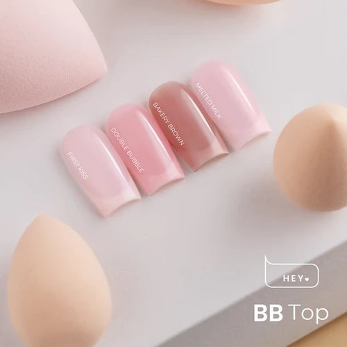 Four artificial nails in pink and nude UV gel polish shades with makeup sponges on a white background.