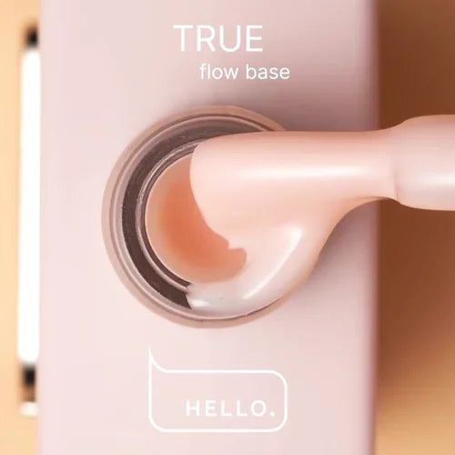 Close-up of a pink UV nail gel bottle with brush, labeled true flow base, for manicure.