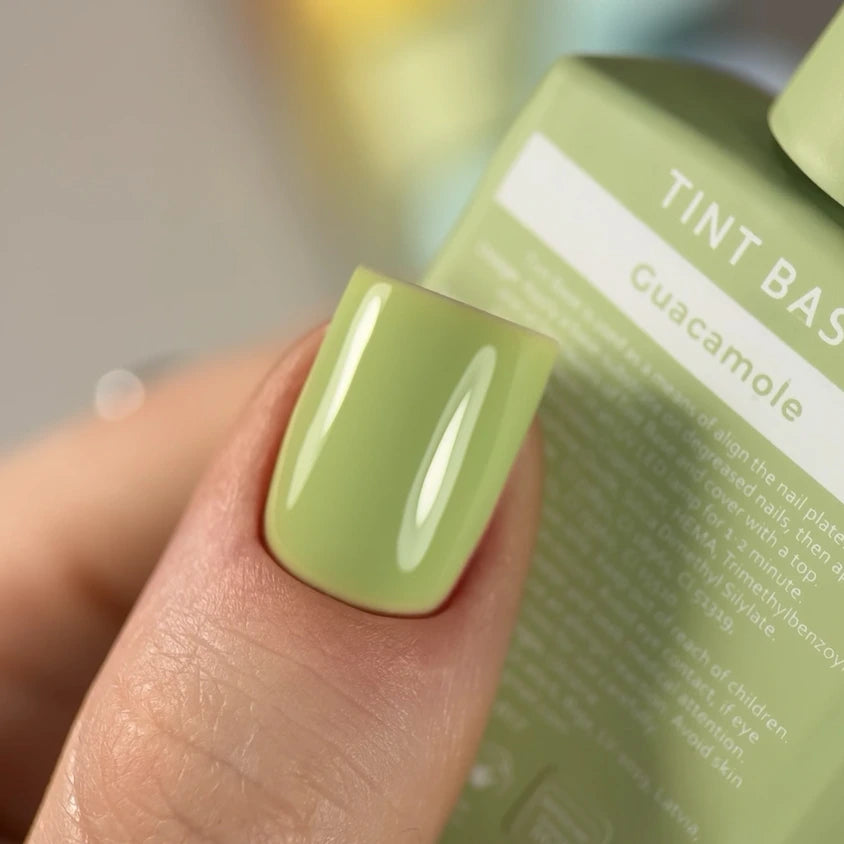 Close-up of fingernail with glossy light green guacamole gel nail polish manicure