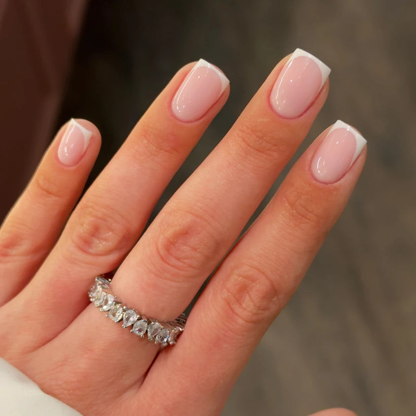 Hand with classic French manicure and diamond ring, professional nail art closeup