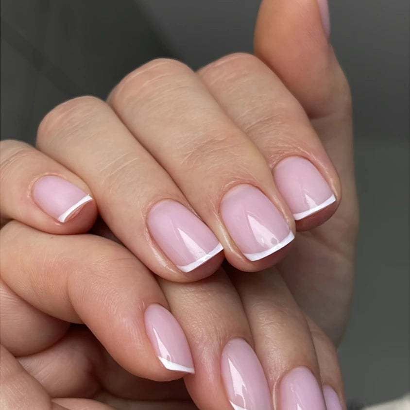 Short nails with classic French manicure, pink base and white tips, professional nail art