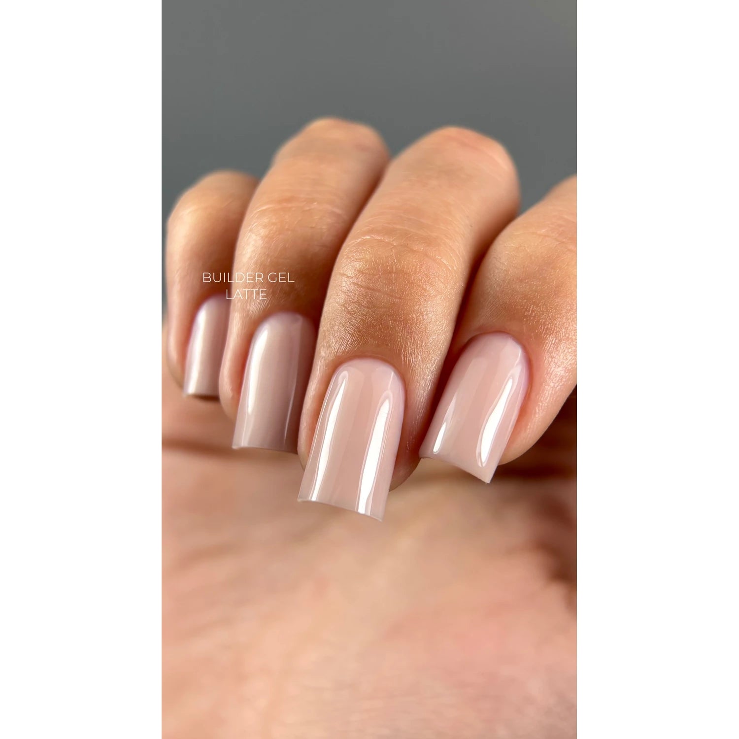 Hand with long square nails featuring glossy nude builder gel latte manicure