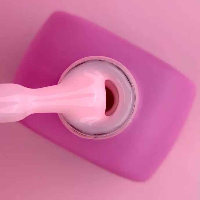 Close-up of pink UV nail gel in bottle with applicator brush, professional nail product