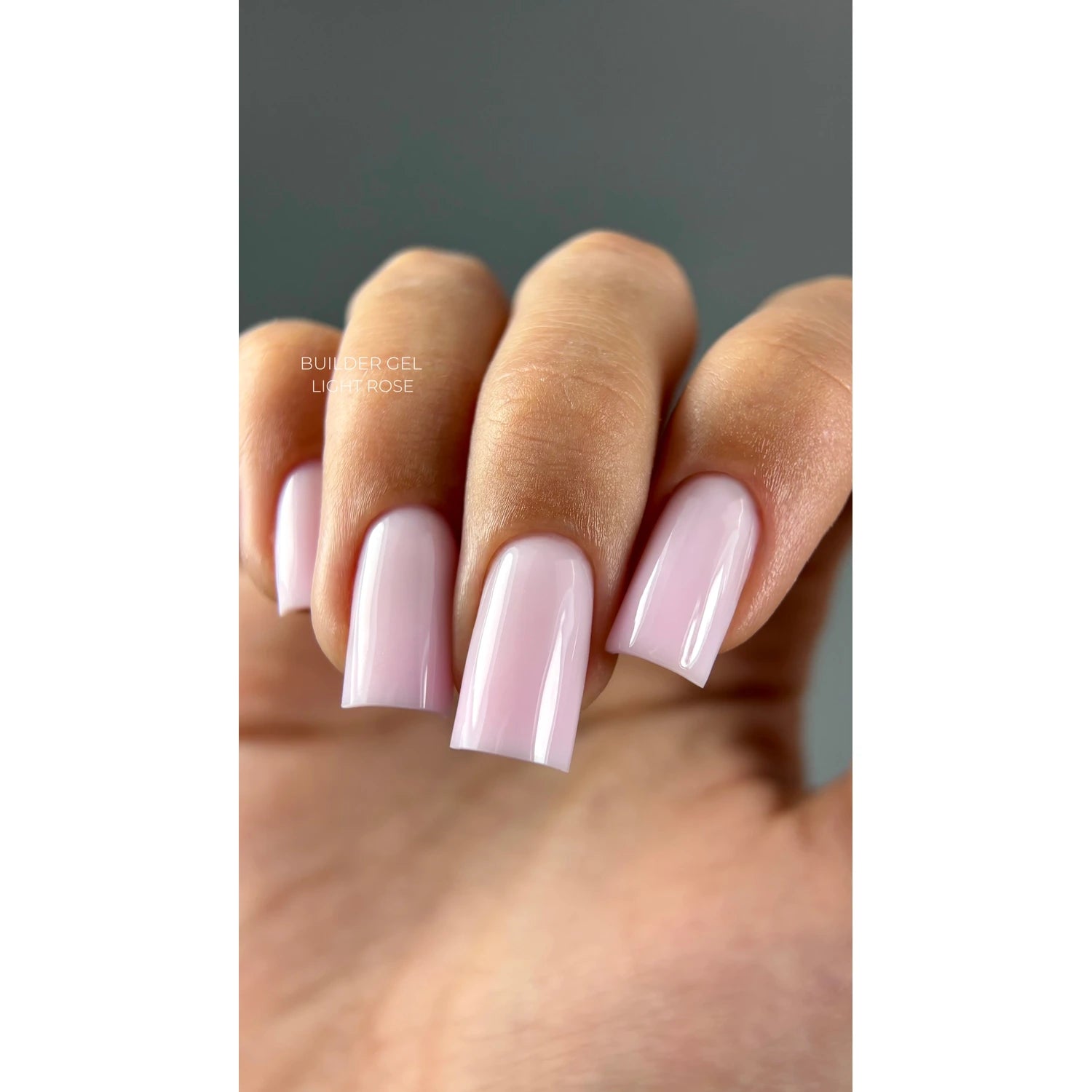 Hand with glossy light rose builder gel manicure, square-shaped nails, close-up