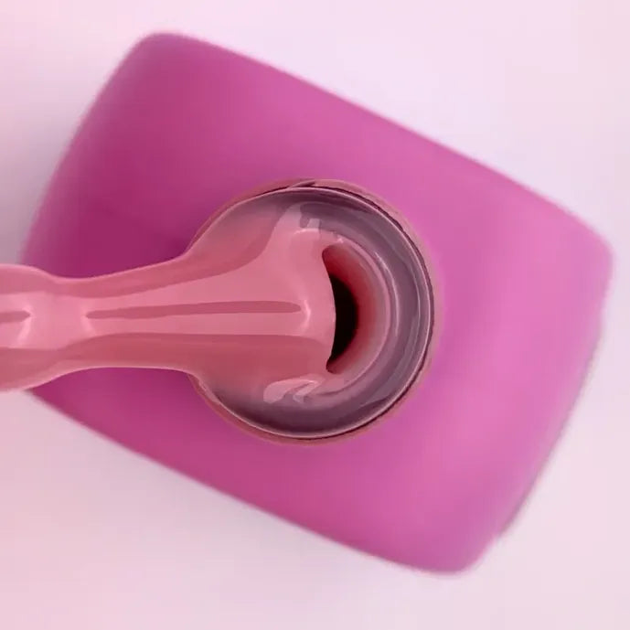 Pink builder gel being scooped from an open jar, ideal for nail extensions or manicures