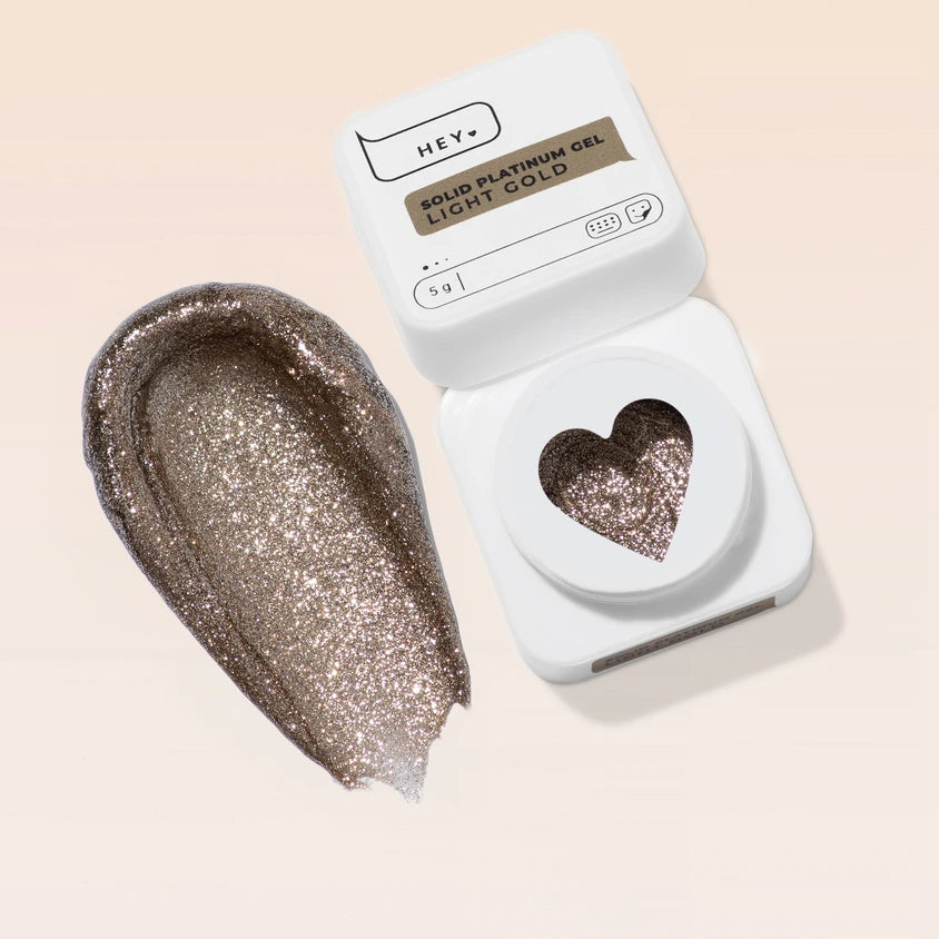 Light gold glitter solid platinum gel for nails, swatched beside open container with heart shape.
